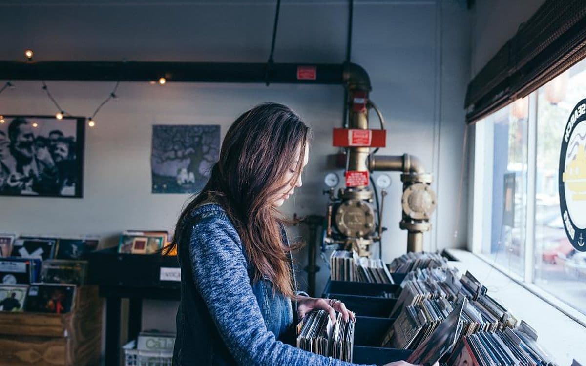 A woman flipping through crates of records in a small record shop.