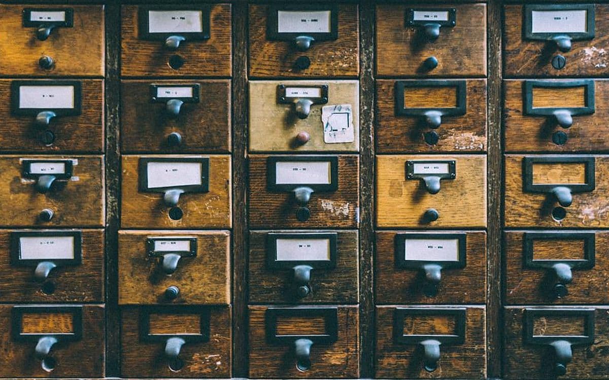 Rows of old wooden card-catalogue drawers, each with a small paper label.