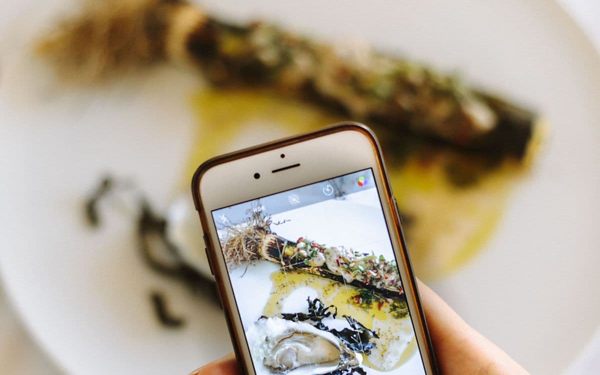Someone photographing a plated dish with their phone.