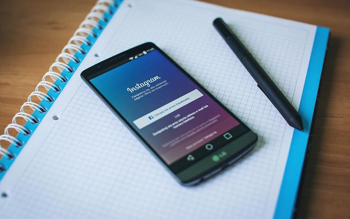 An Android phone showing the Instagram sign-in screen, lying on a grid notebook next to a pen.