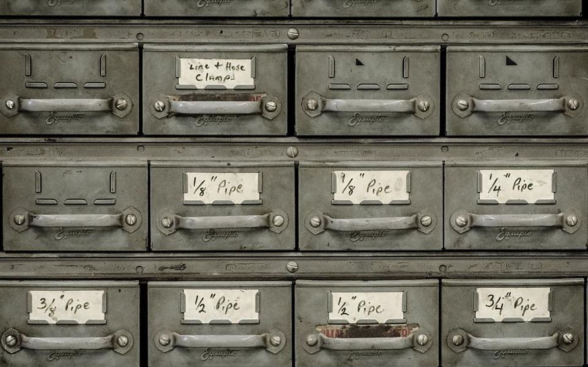 A grey metal cabinet of small labelled drawers.