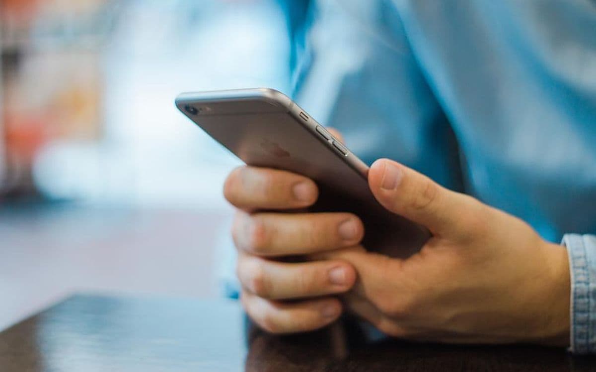 Two hands holding a phone at a desk, mid-scroll.